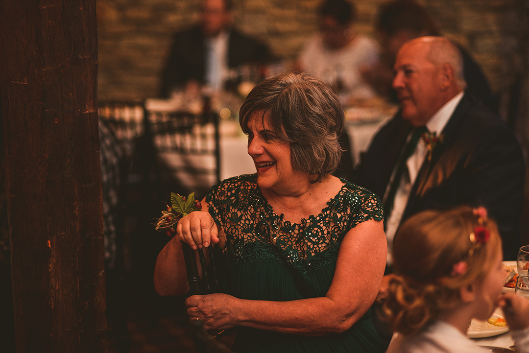 the mother of the groom laughing as the best man gives a speech