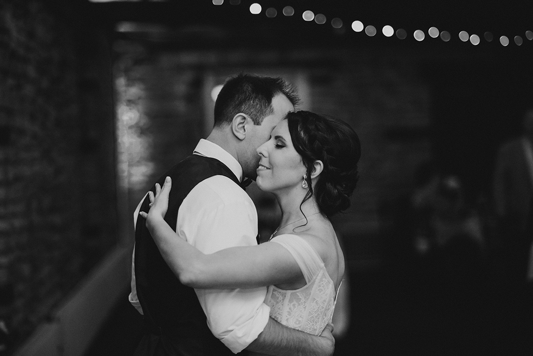 a bride smiling as she dances with her husband during their first dance at a historic building in Lockport