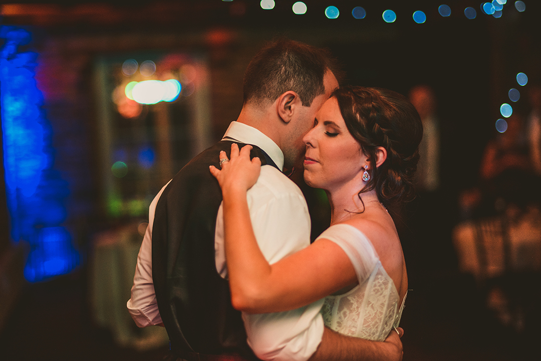 a bride and groom with their arms around each other as they experience their first dance in Lockport