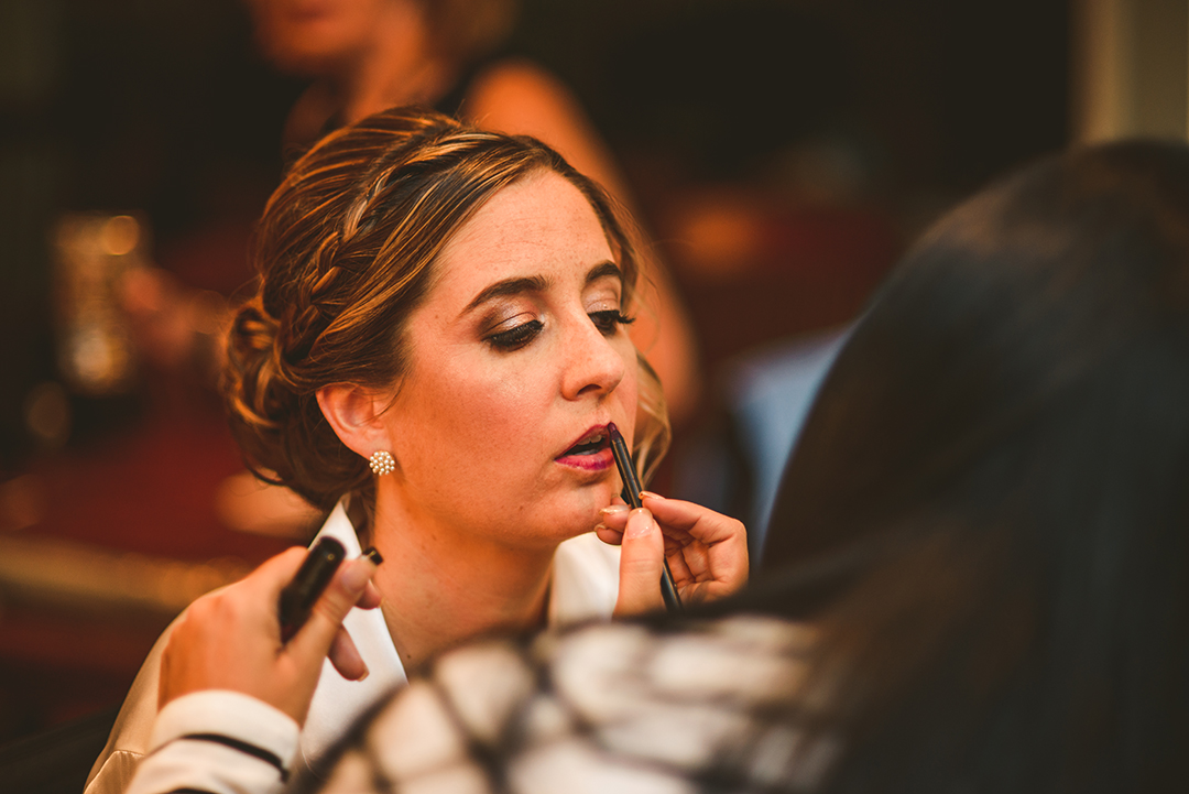 the makeup artist applying lip stick to the bride at her family home in Naperville IL