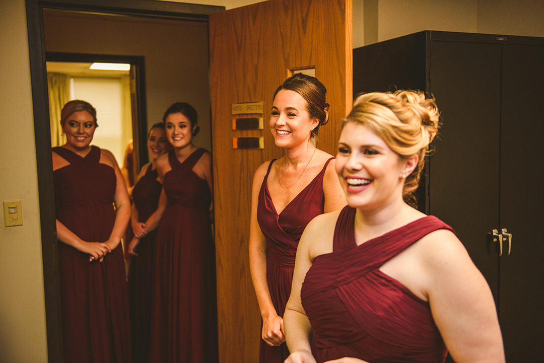 all of the bridesmaids smiling as the bride cries while reading a letter from her groom at St Thomas Apostle Church in Naperville