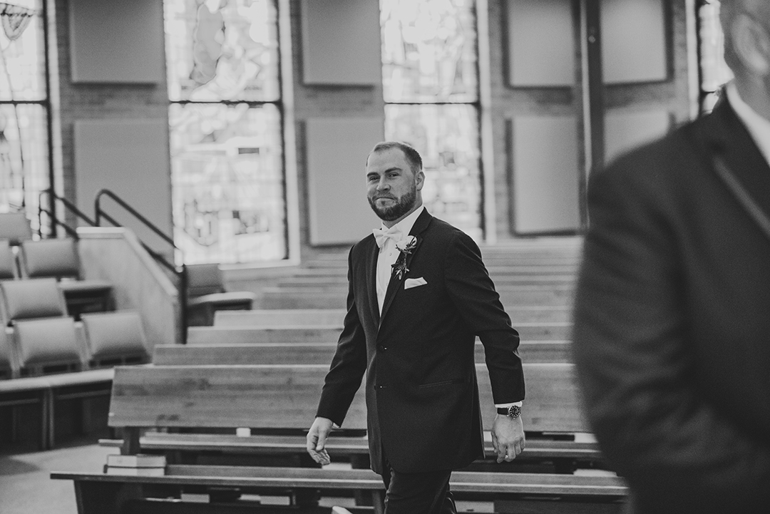 the groom smiling as he walks down the aisle at St Thomas Apostle Church in Naperville just before getting married