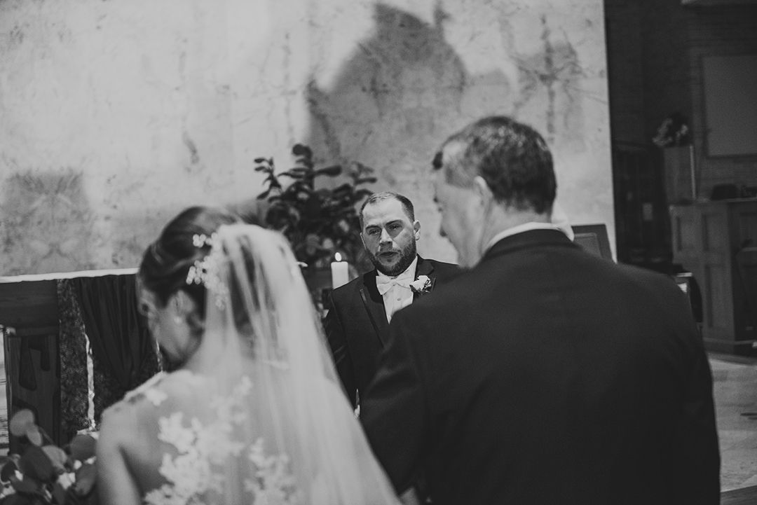 the groom crying as the father of the bride walks his little girl down the aisle