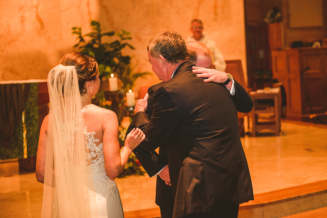 the groom hugging the father of the bride as he hands her off to him at St Thomas Apostle Church in Naperville