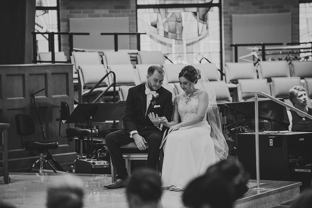 the groom looking at his brides hands on the alter during their wedding ceremony at St Thomas Apostle Church in Naperville