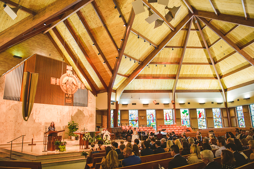 a wide shot of a wedding taking place at St Thomas Apostle Church in Naperville with a tall wooden roof