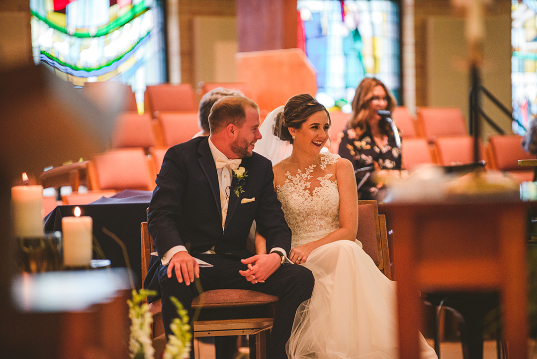 the bride and groom laughing at the alter at St Thomas Apostle Church in Naperville during their wedding ceremony