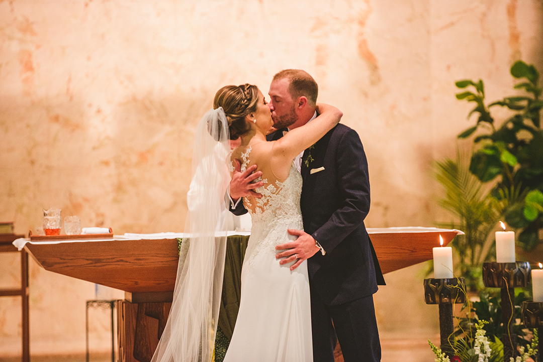 the bride and groom kissing for the first time as husband and wife at St Thomas Apostle Church in Naperville