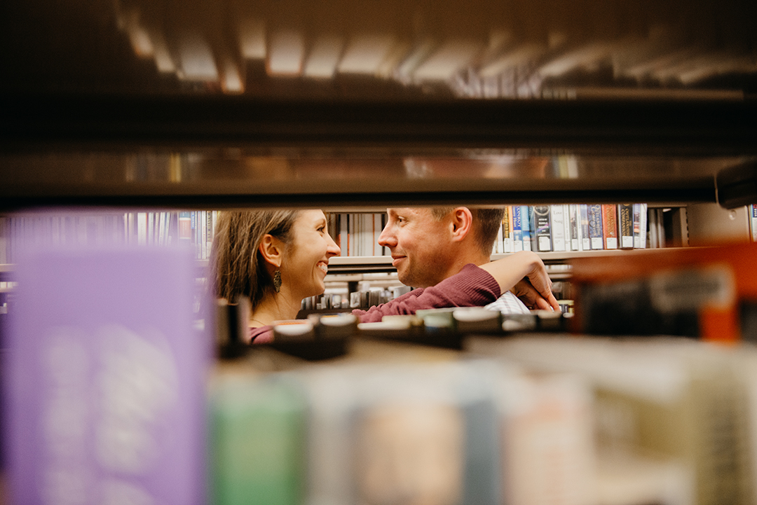 a bride with her arms around her groom in a Naperville library surrounded by books