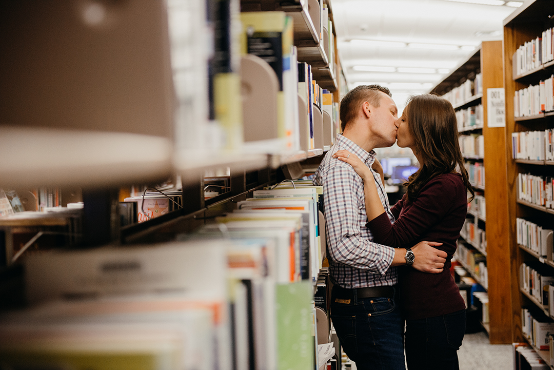 a bride kissing her groom on a shelf of old books at a library in Naperville