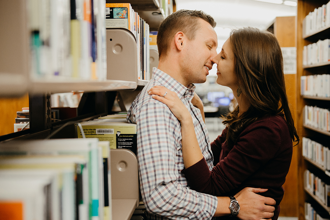 a bride about to kiss her groom against a row of old books at a library in Naperville