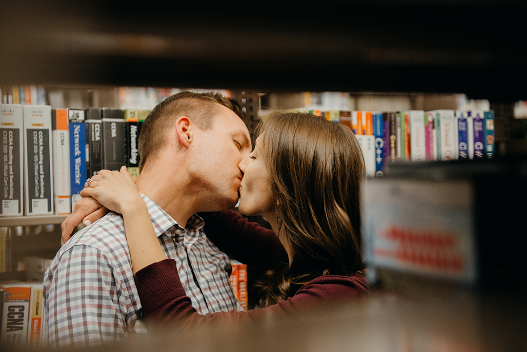 a bride and groom kissing between a row of old books at a library in downtown Naperville
