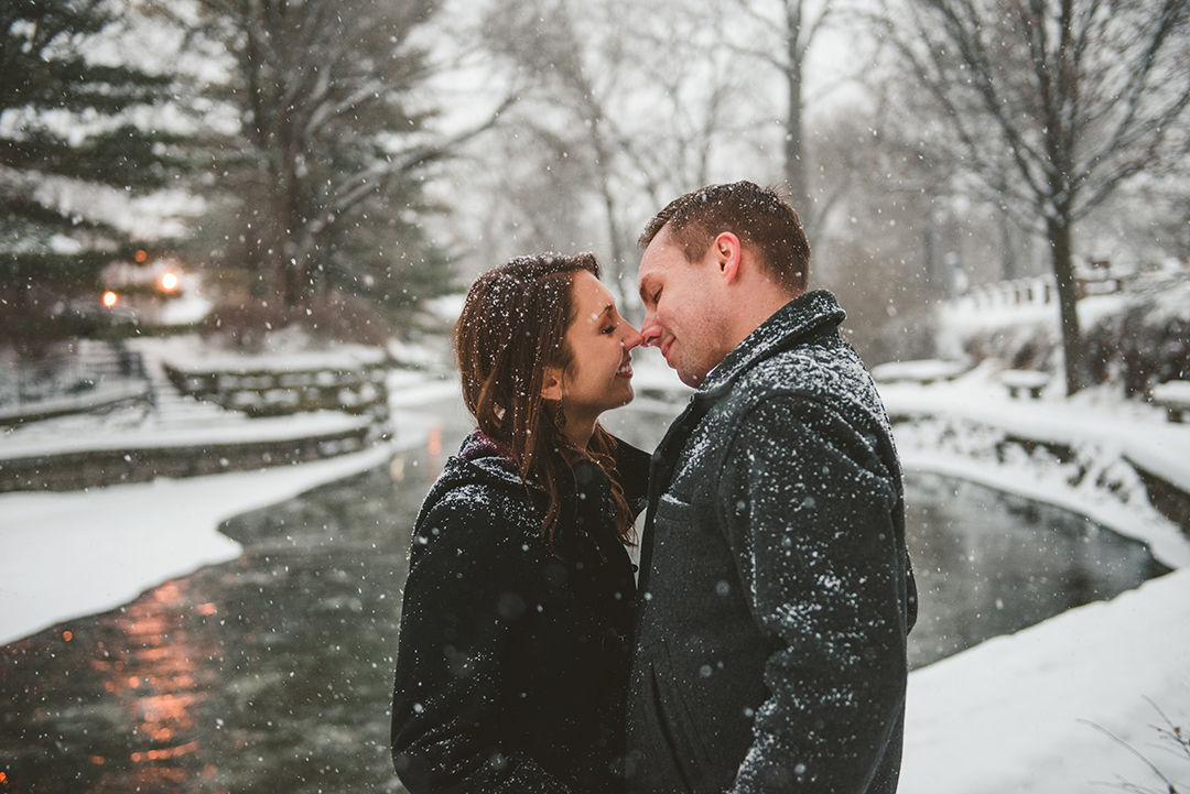 a bride and groom about to kiss as they stand by a quiet frozen river on the Naperville Riverwalk