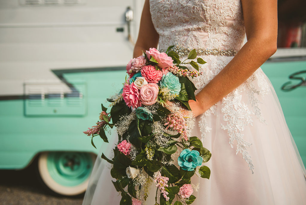 a tattooed bride standing with her flowers in front of an old baby blue trailer at the Warehouse 109 in Plainfield