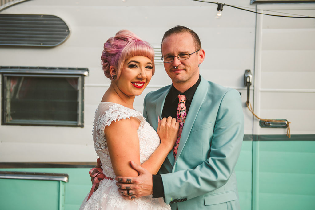 a tattooed bride and groom standing in front of an old airstream trailer in the warm light of the setting sun at the Warehouse 109