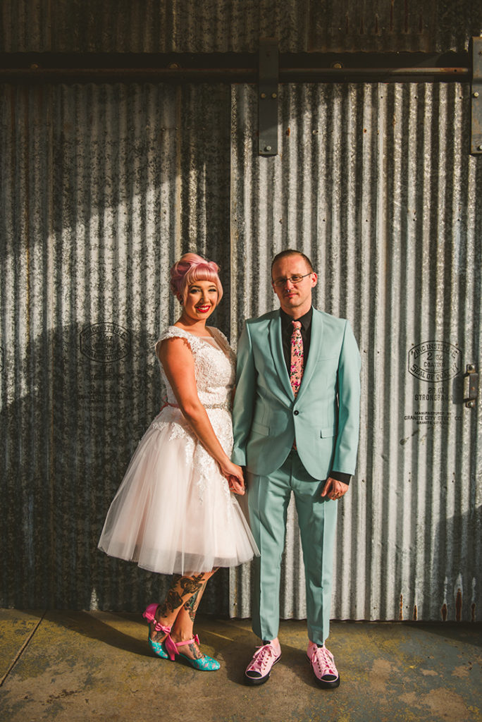 a tattooed bride and groom standing in front of rustic metal at the Warehouse 109 in Plainfield