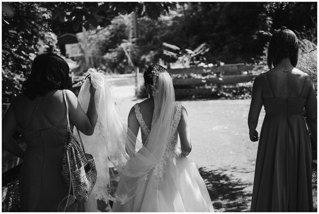 bridesmaids helping a bride carry her dress before they head to the wedding ceremony