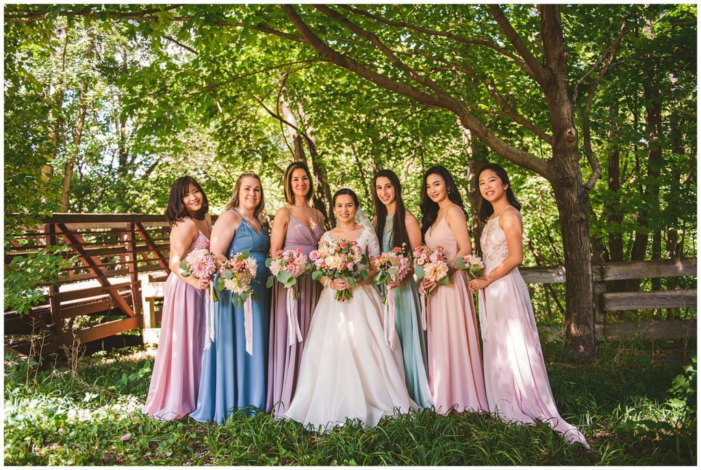 hot bridesmaids standing next to the bride by a old wooden bridge at a summer lake wedding
