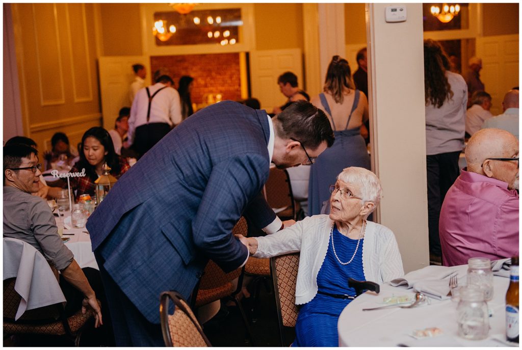 the groom talking to his grandmother at a wedding reception at Epiphany Farms Restaurant in Bloomington Illinois