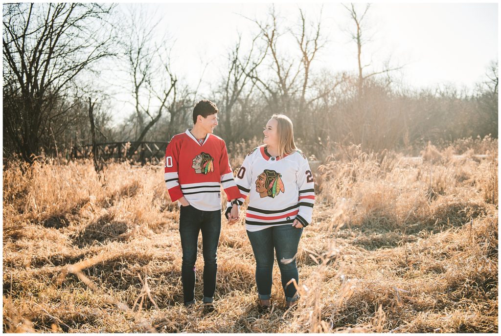 a bride and groom wearing black hawks jerseys at an engagement session in the early morning of winter