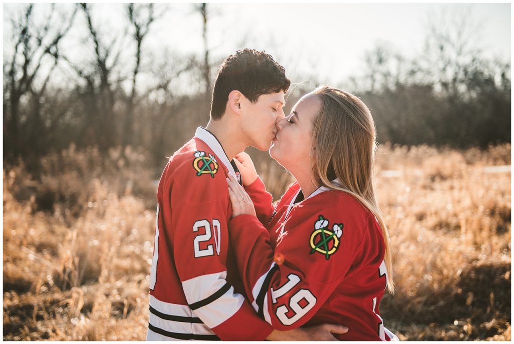 a bride and groom kissing in black hawk jerseys in the early morning of winter
