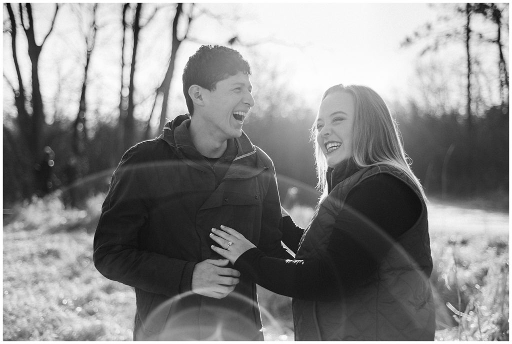 Rustic Engagement Photos of a bride and groom laughing in a field just after they kissed in black and white