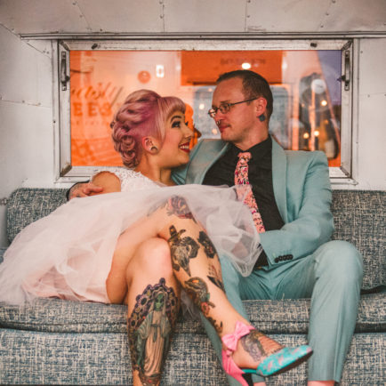 one of the Chicago wedding photographers photographing a tattooed bride and groom sitting with each other as they laugh in an air stream