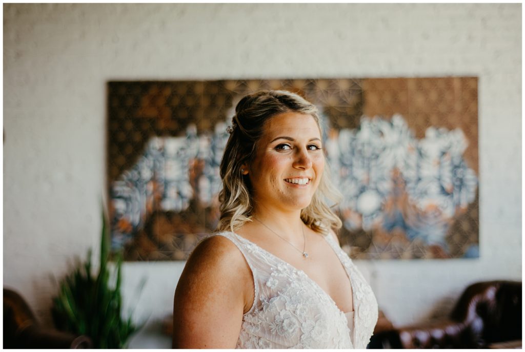 a bride smiling on her wedding day in front of a painting at Society 57