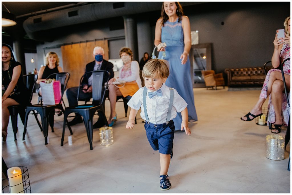 the ring bearer running down the aisle at a wedding at Society 57 in Aurora