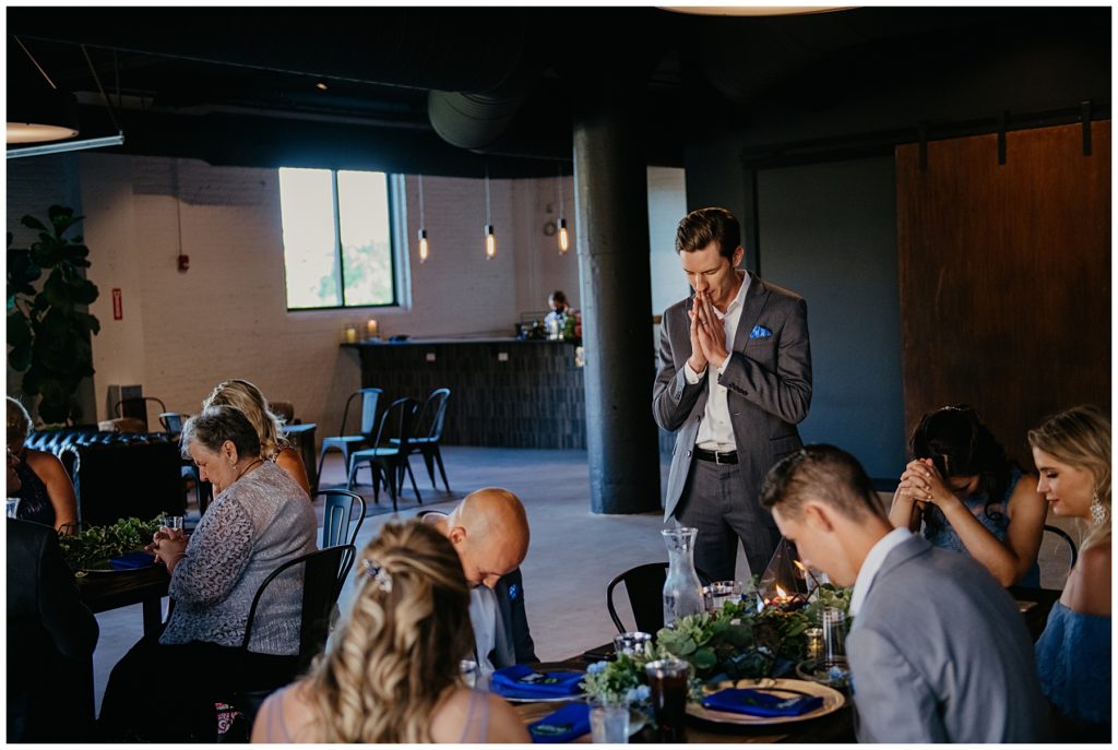 the officiant praying during a wedding reception at Society 57 in downtown Aurora