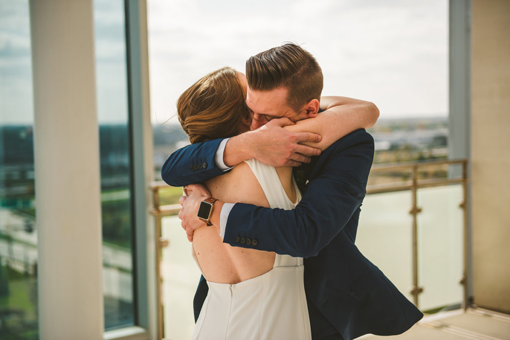 a groom seeing his stunning bride for the first time on a roof of a building as they hug each other deeply