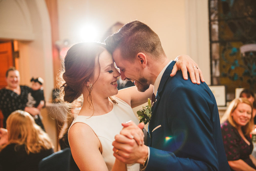 a husband and wife dancing for the first time together as their close friends and family watch