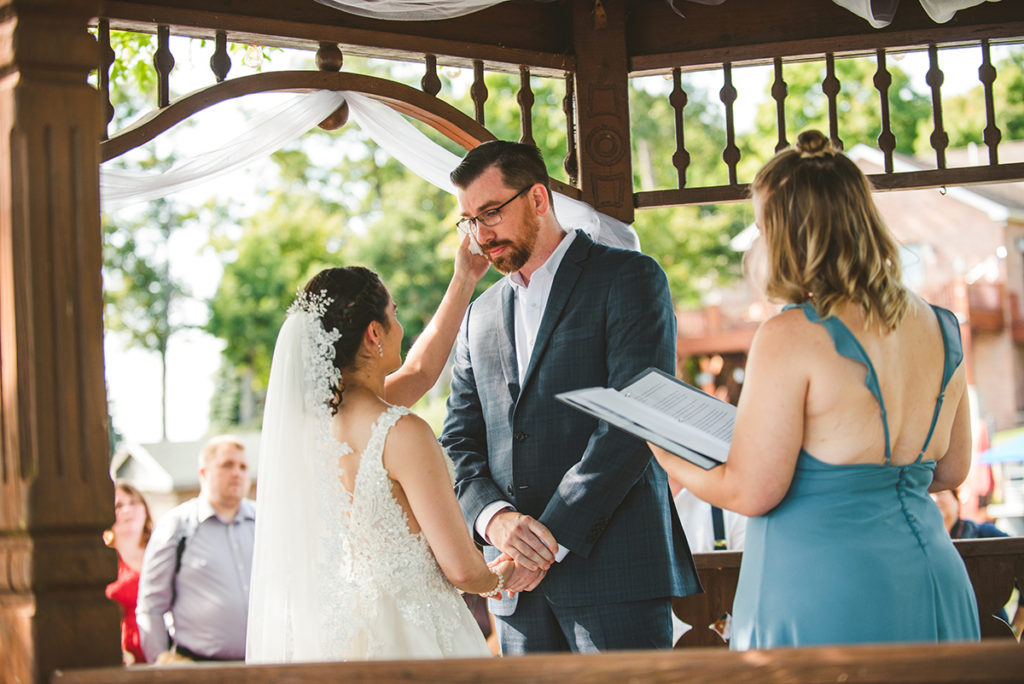 a beautiful thai bride whipping a tear from her groom during their wedding ceremony
