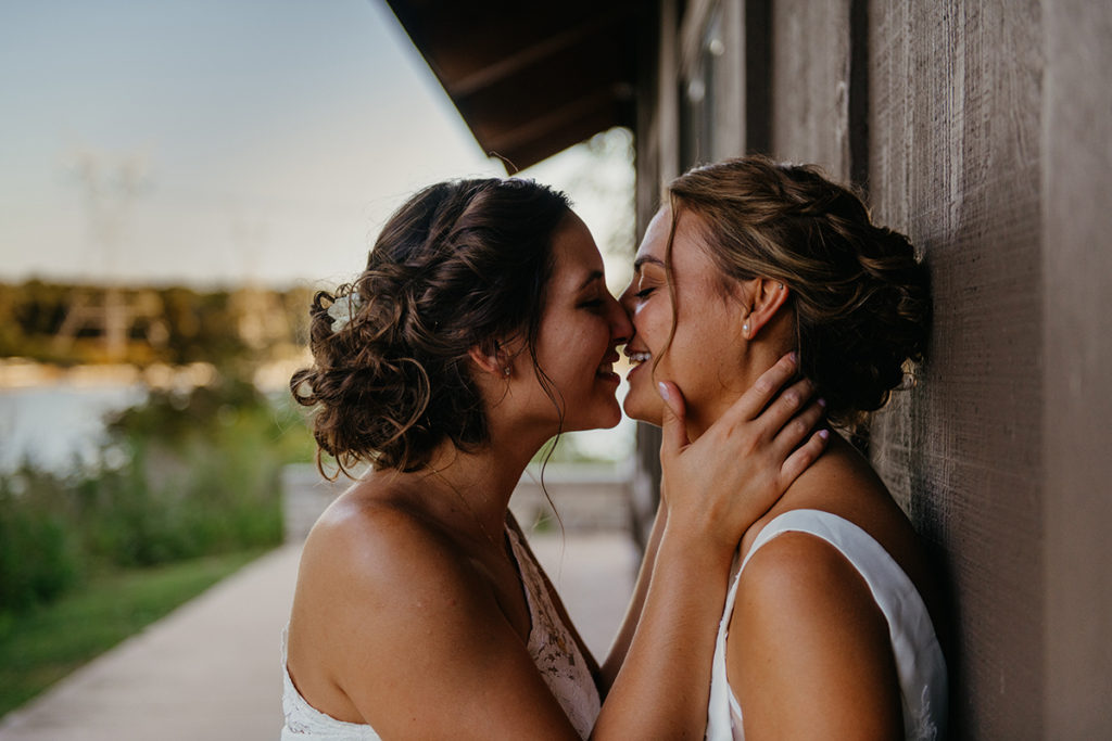 two brides kissing as the sun sets in the background as they smile on their intimate wedding