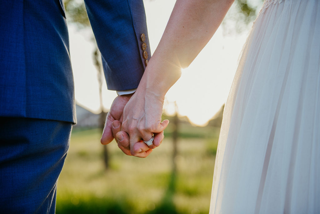 a husband and wife holding hands with the setting sun in the background