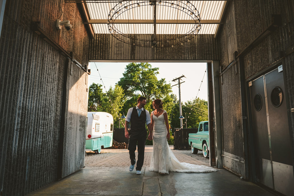 a bride and groom walking into Warehouse 109 as they smile at each other in the evening