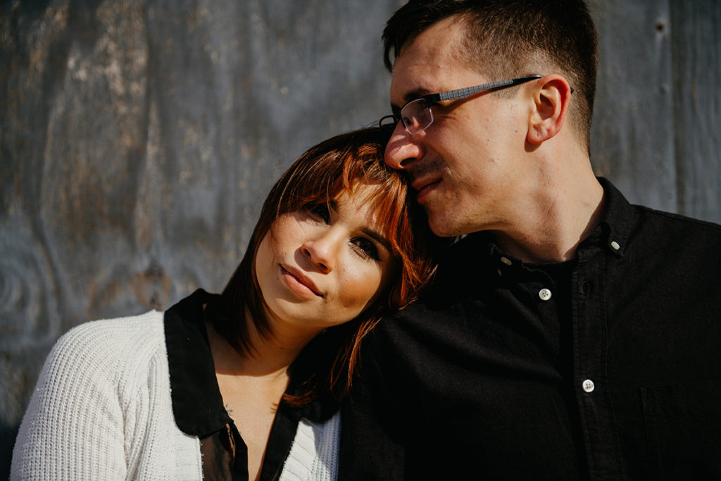 a woman resting her head on her fiances shoulder as he leans into her