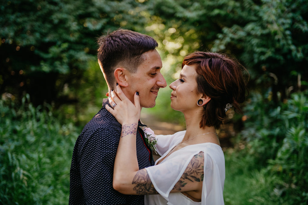 a man and a woman who just got married at their micro wedding as they smile together in the woods
