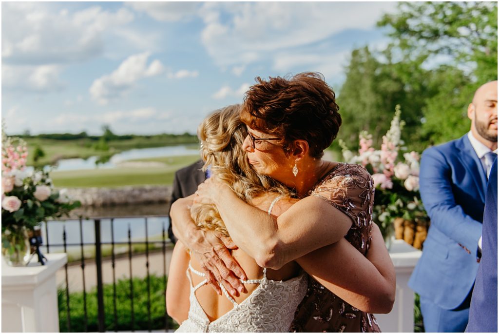 the mother of the bride hugging the bride as she is about to get married on a balcony at Mistwood Golf Club