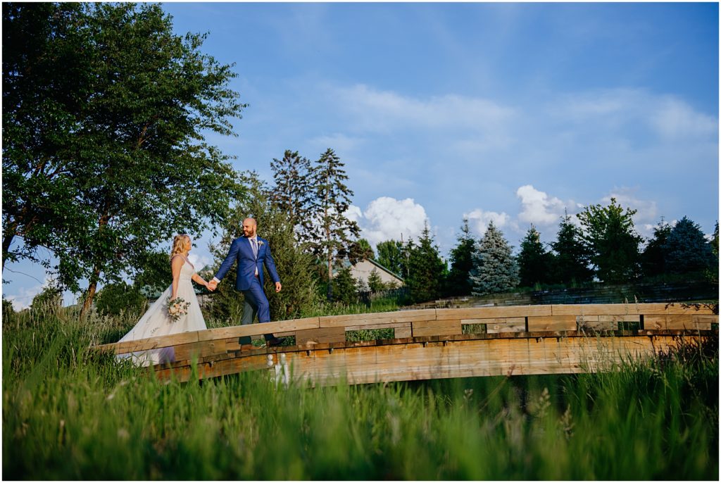 the groom leading his bride down a old wooden bridge at Mistwood Golf Club in Romeoville