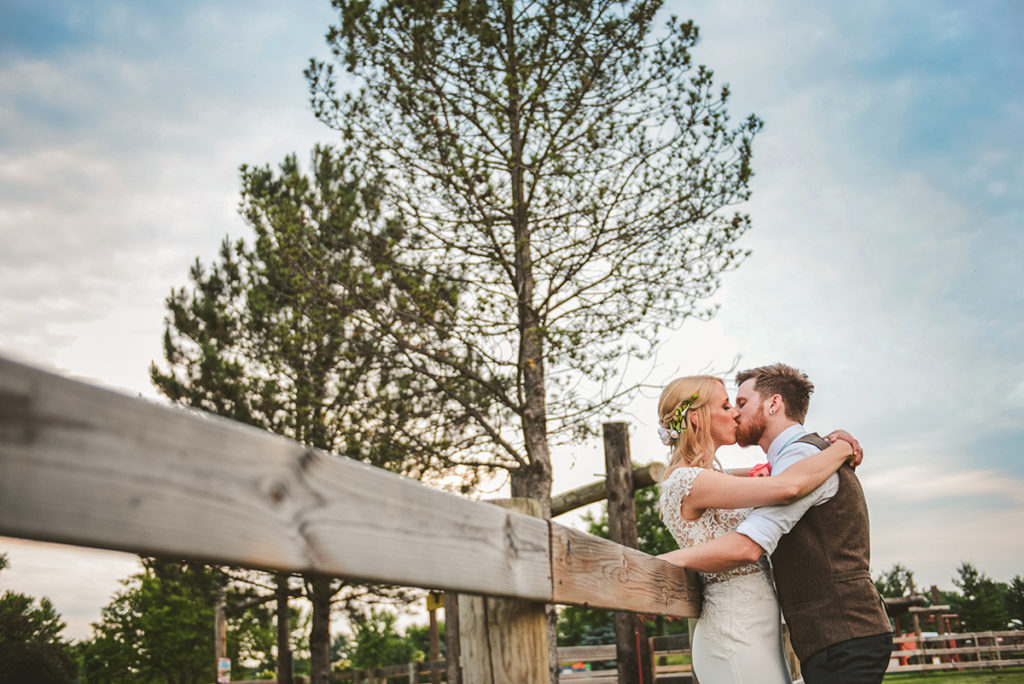 a married couple standing in an apple orchard as the sun sets in the evening