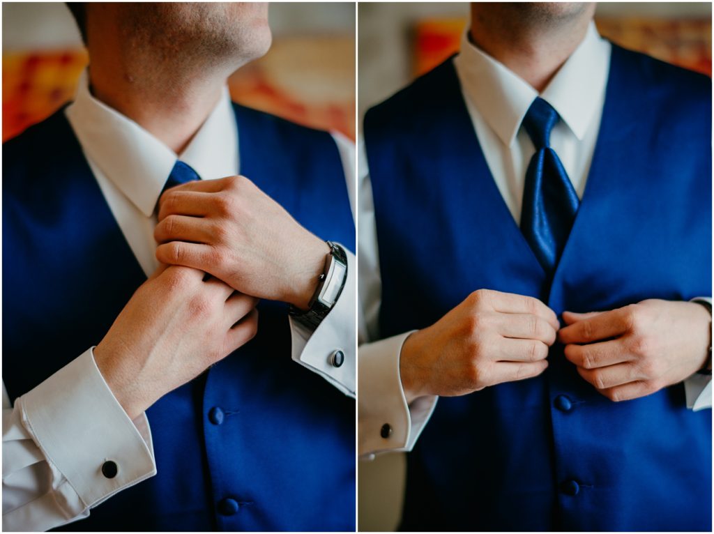the groom adjusting his tie and vest as he gets ready for his wedding