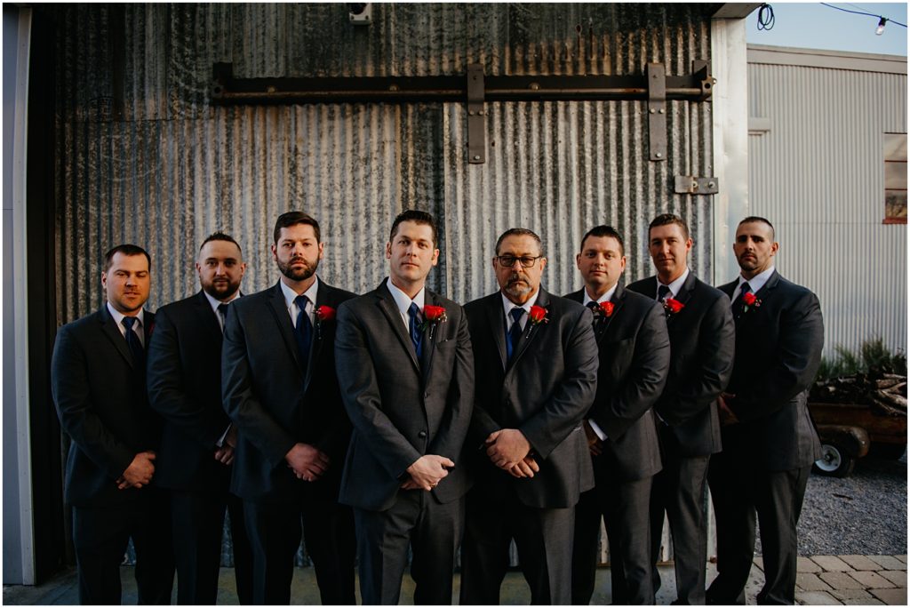 the groomsmen standing with the groom on a winter evening at a warehouse wedding