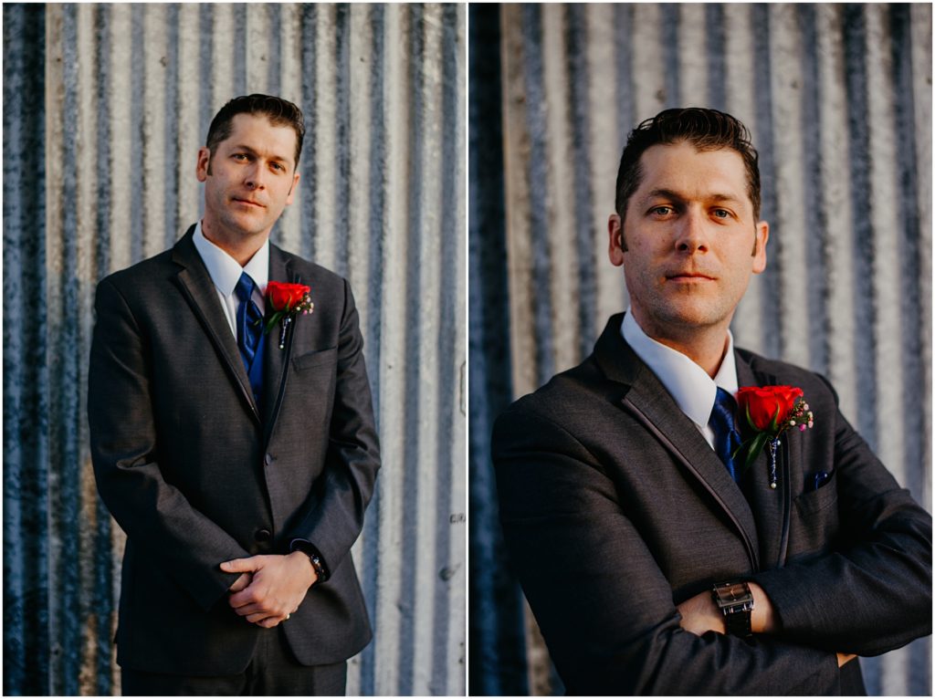 the groom standing in front of old metal walls with warm light shining on him at his warehouse wedding