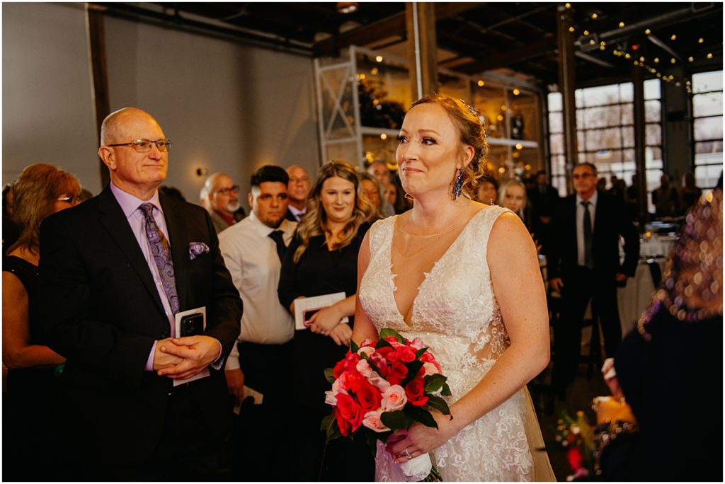 the bride walking down the aisle at her winter warehouse wedding