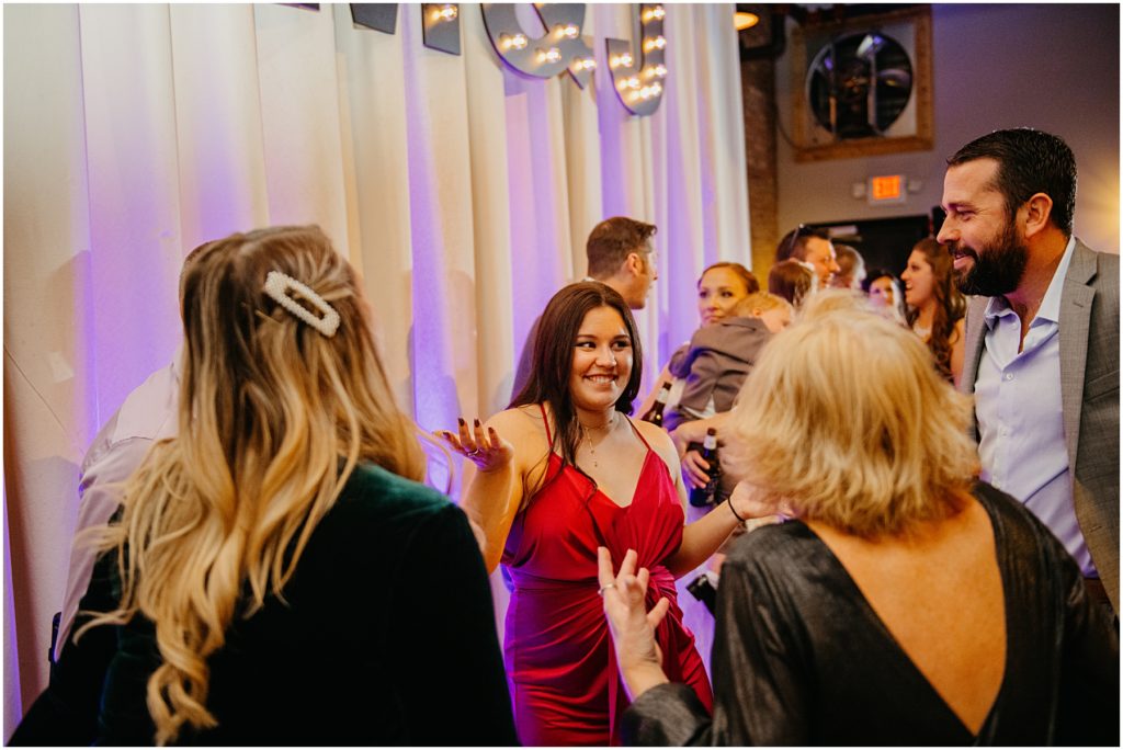 a woman in a red dress dancing as she laughs at a winter warehouse wedding