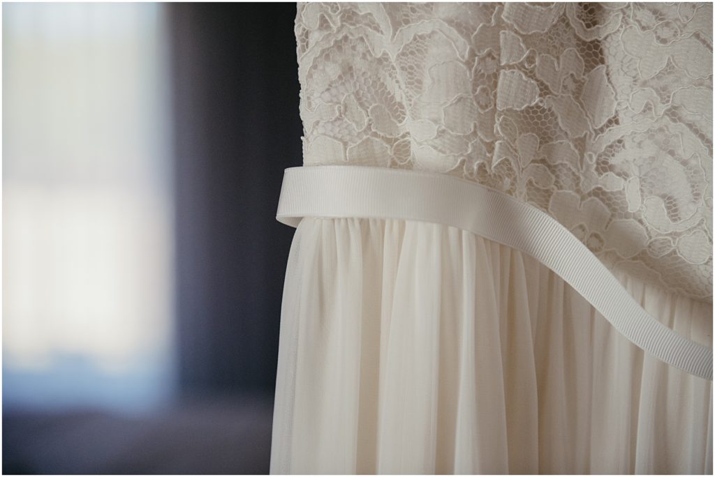 A white wedding dress hanging in a hotel room