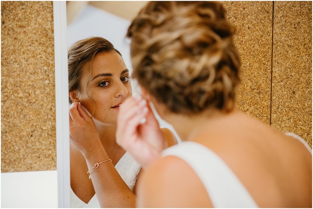 a bride putting on her earrings before her wedding