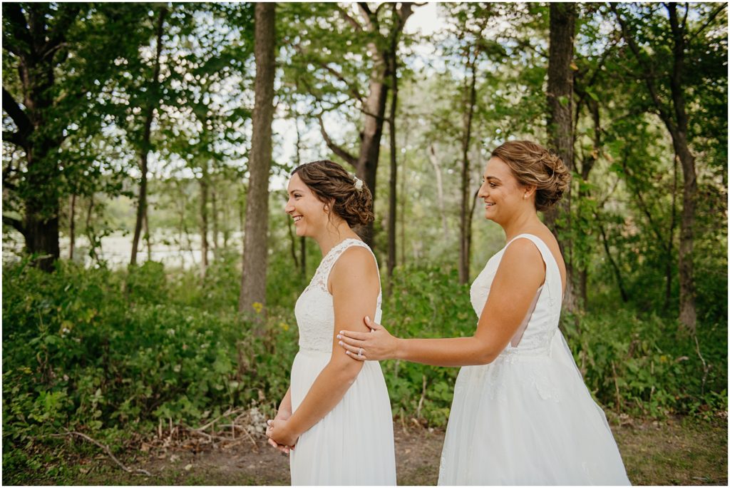 two brides experiencing their first look on a secluded wooded trail