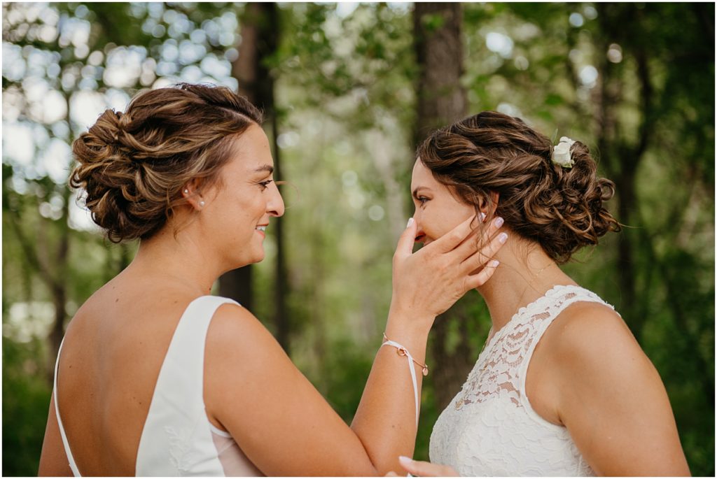 a bride brushing a tear away from her brides face during their first look at their intimate wedding